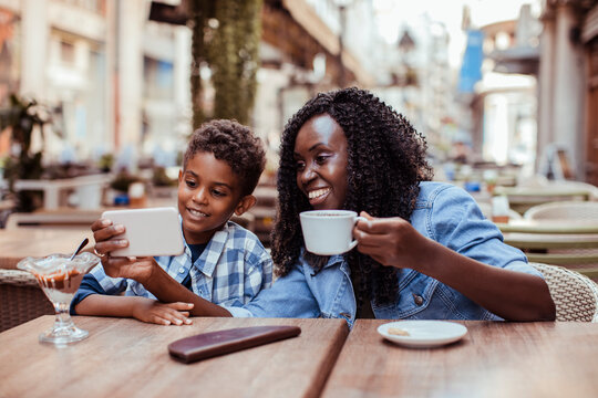 Parent and child using smartphone at outdoor cafe