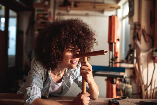 Young woodworker sighting along a dowel in a workshop