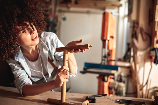 Woman assembling wooden furniture in workshop