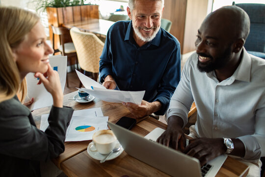 Diverse business team reviewing charts at cafe