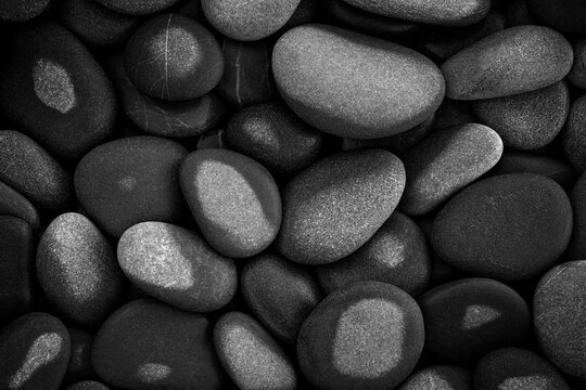 Abstract background textured with smooth, black round, wet pebbles. close-up sea beach with pebbles for website banner template page design.