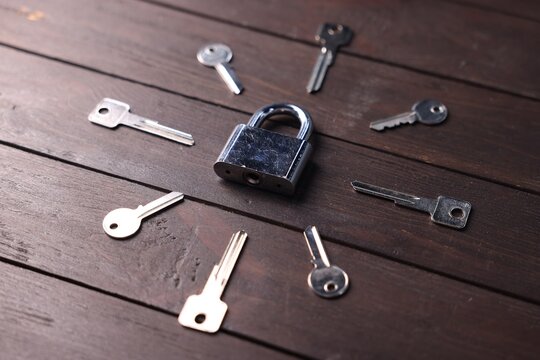 Different keys and lock on wooden background, closeup