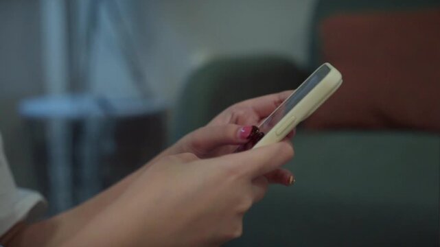 Detail shot of woman using mobile phone, scrolling through social media feed. Concept of doom scrolling, internet browsing, or texting.