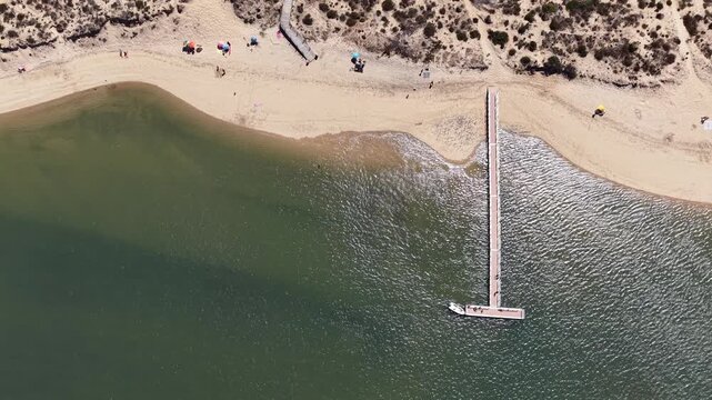 Aerial view of a boat docking at a wooden pier in vila nova de milfontes