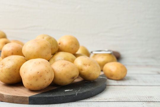 Ripe raw young potatoes on white wooden table, closeup. Space for text