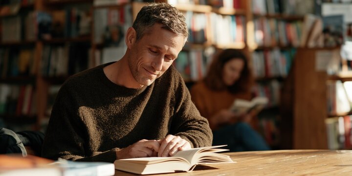 Thoughtful man studying a book in a sunlit bookstore background for quiet learning and reading lifestyle scenes