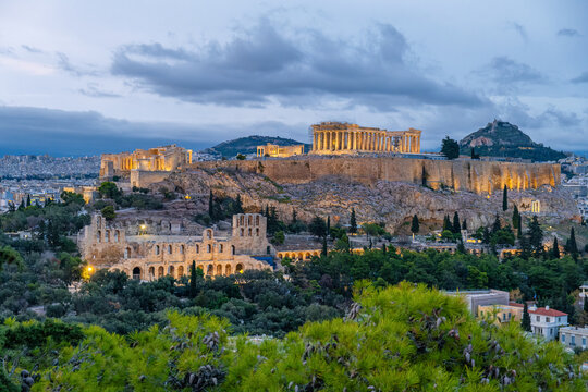 Evening view of Acropolis of Athens with illuminated Parthenon temple and Odeon of Herodes Atticus surrounded by the city. Greek travel destination for tourism, architecture, history, city breaks