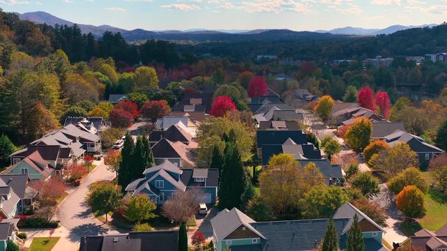 Quiet suburban homes nestled among wooded mountain slopes. Vibrant fall foliage transforms surrounding landscape into colorful panorama.