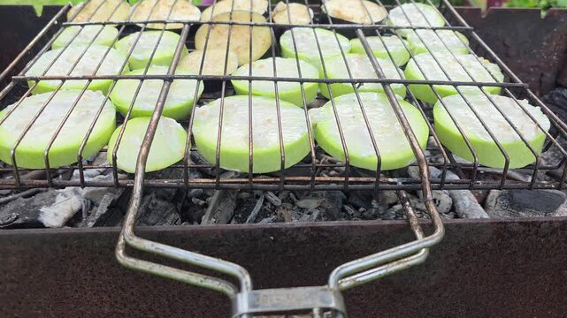 Grilling zucchini and eggplant over hot coals in an outdoor setting