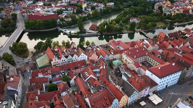 Aerial drone view of a weir on the Isar river beside the old town with its red rooftops and gabled houses, Landshut, Germany