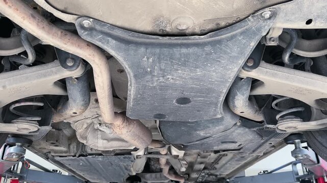 The underside of a car is shown with a lot of dirt and grime. The car is old and has been neglected for a long time. Concept of abandonment and neglect