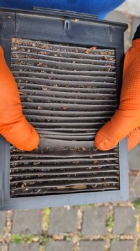Close-up of a dirty car cabin air filter clogged with dust and debris. 