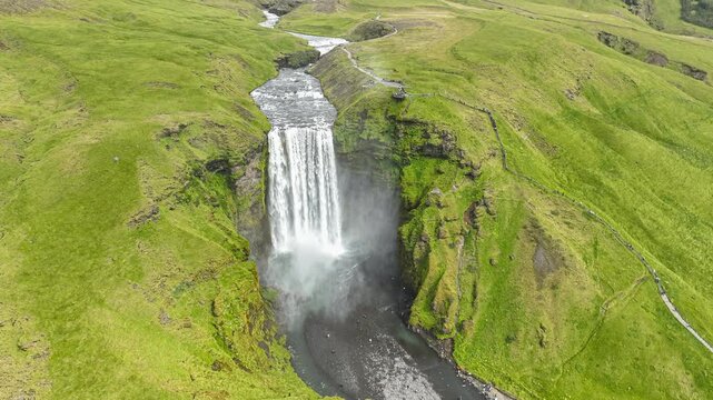 Aerial drone flying forward approaching Sk&oacute;gafoss waterfall and flying over the crest river in Iceland