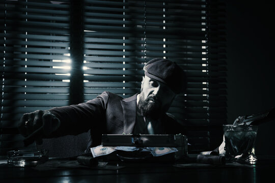 Mafia. Man with gun, cigar, whiskey and case of dollar banknotes at table in dark room