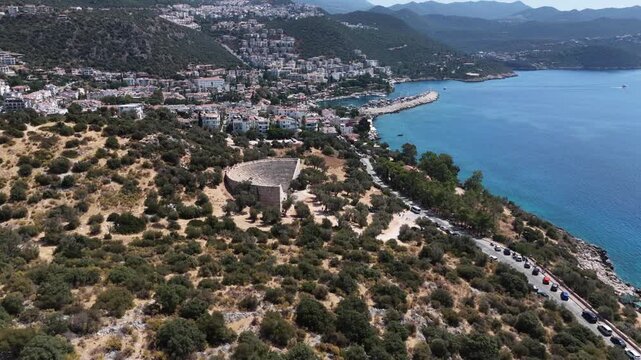 Aerial forward flight over the Antiphellos Ancient Theater and coastal road approaching the town of Kas, Turkey.