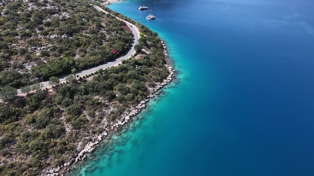 Aerial forward flight along a scenic coastal road and beautiful rocky shoreline with deep blue Mediterranean sea.