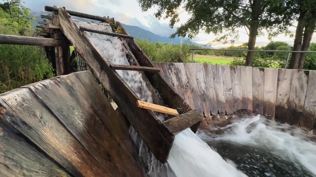 Water flow trough with a vintage wooden swirl washing machine and a wooden handle