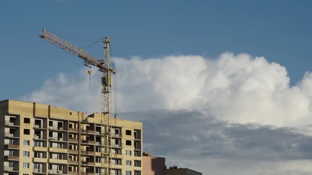 Construction cranes operate next to apartment facades under dramatic cloud formations Natural daylight creates shadows and highlights across brick surfaces and window glass Shots include close ups of 