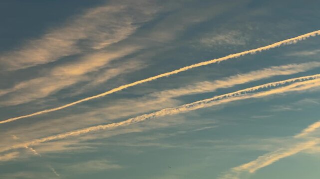 The sky is blue with white clouds and chemtrails