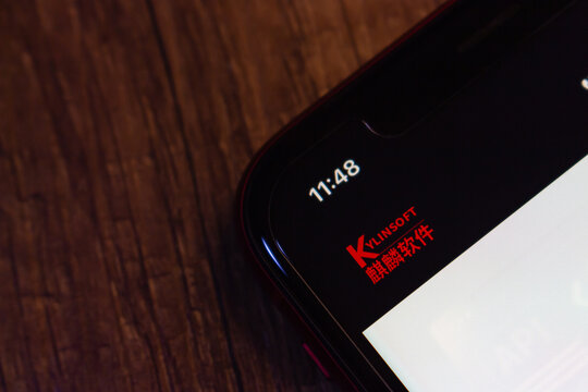Mexico City, MEXICO - Sep 1 2026 : Close-up of a smartphone on a dark wooden surface displaying the red KylinSoft logo and 麒麟软件 wordmark at the top of a dark screen, above a white content area.