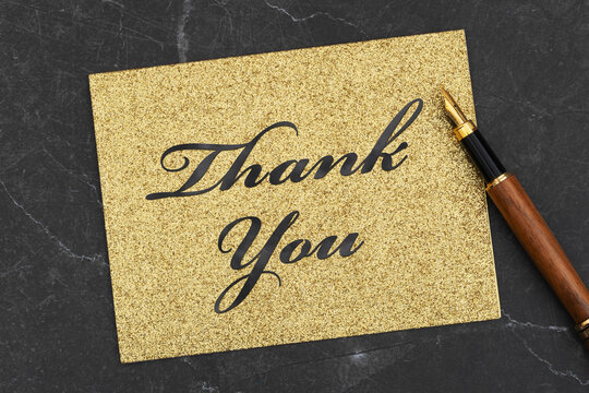 Thank you message on gold glitter greeting card on black stone