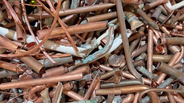 Zooming into a heap of scrap copper pipes waste from the plumbing industry ready to be recycled