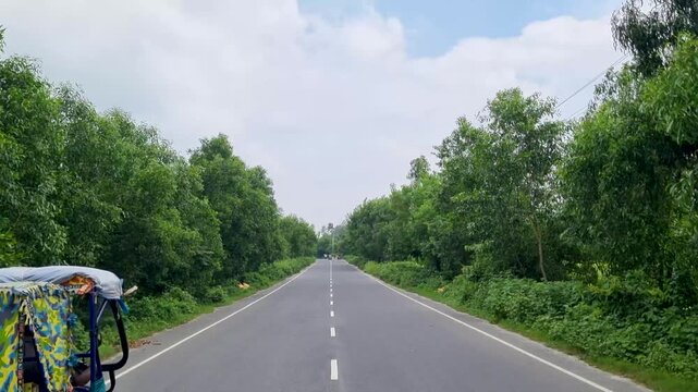 Two motor rickshaws traveling on a scenic countryside highway surrounded by greenery