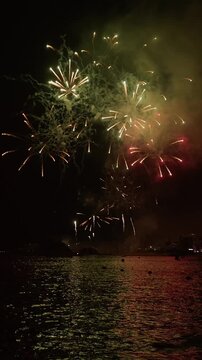Fireworks over sa Palomera reflected on the sea, Blanes, vertical