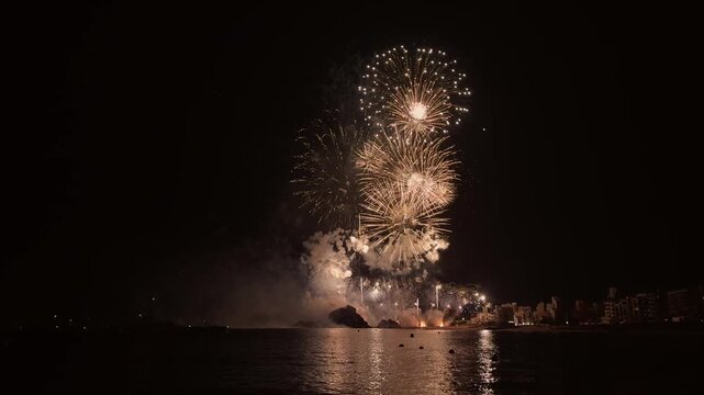 Golden fireworks bursting over sa Palomera rock in Blanes, Spain