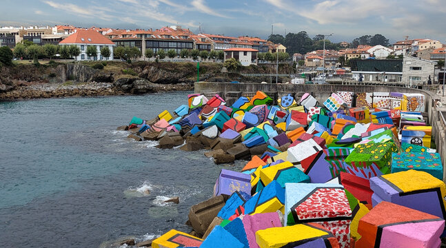 Colorful painted concrete breakwater blocks known as "Los Cubos de la Memoria" by artist Agust&iacute;n Ibarrola line the harbor entrance of Llanes, Asturias, Spain
