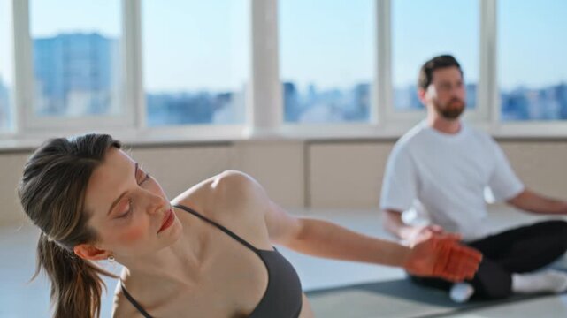 Two young people side bend stretch bright yoga studio. Closeup workout class.