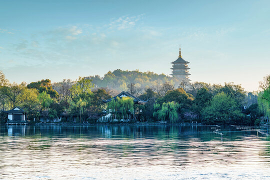 Leifeng Pagoda rises above West Lake in Hangzhou, surrounded by traditional gardens and willows on a peaceful clear morning.