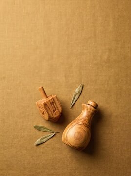 Olive wood objects including a spinning top and a bottle on a linen background with bay leaves, ideal for culinary and decorative use