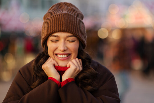 Cheerful woman smiling and holding sweater collar at festive Christmas fair