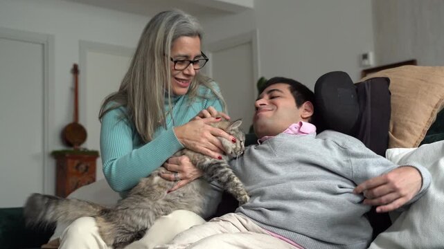 Mother and disabled son bonding with cat on sofa