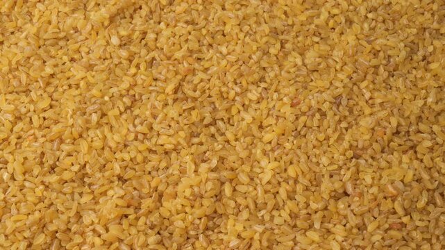 Raw bulgur wheat grains slowly moving close-up