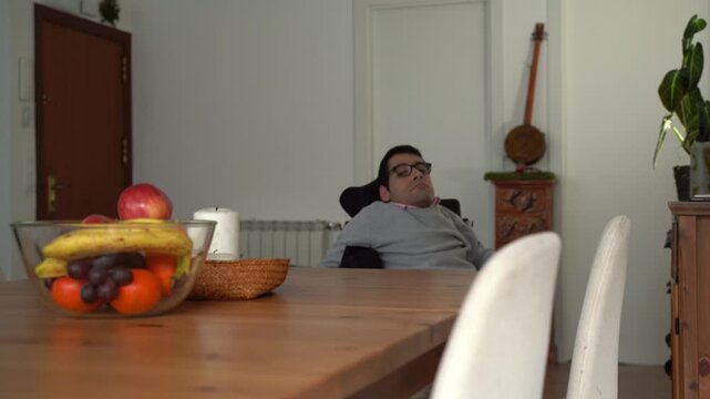 Disabled man in a wheelchair approaching a dining table at home
