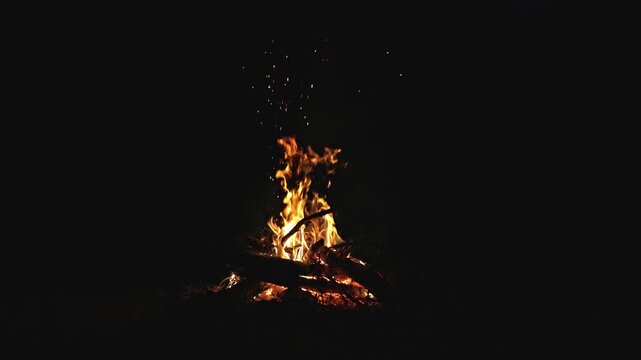 Campfire burning bright at night in darkness.