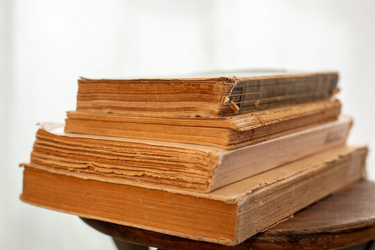 A stack of old books. A collection of antique books neatly arranged on a wooden shelf against a white background. Conceptual themes of history, nostalgia, and old age. Retro style. 