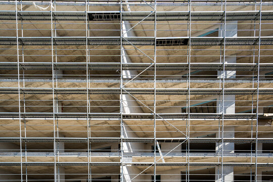 Steel scaffolding in symmetry with a masonry building under construction.