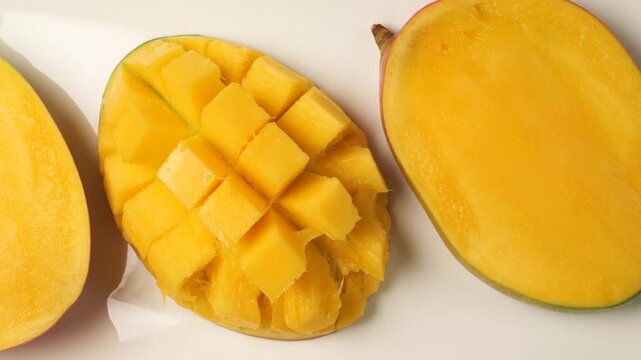 Fresh ripe mango fruit cut in half and diced isolated on a white background