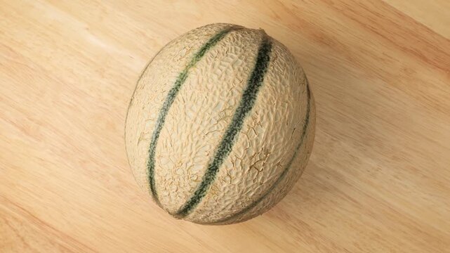 Ripe fresh cantaloupe melon rotating on wooden table