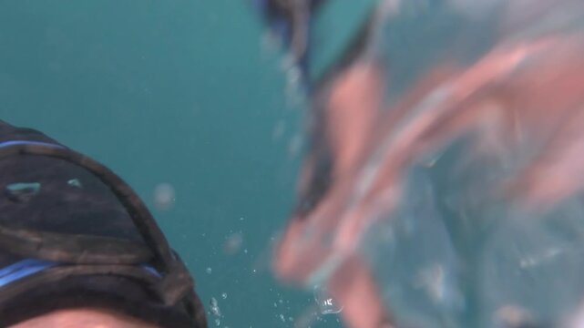 A scuba diver performs a quick backward roll from a boat, splashing into the sea as the camera follows the transition beneath the surface.