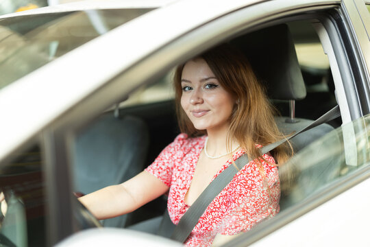 Positive young adult woman driving car during solo trip, side view