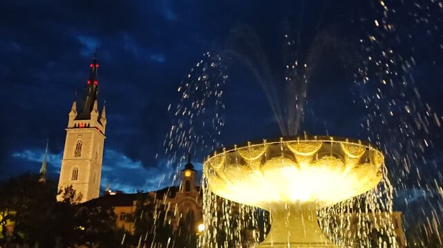 Caslav illuminated fountain with historic town hall tower at night