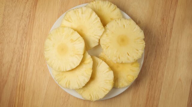 Fresh sliced pineapple rotating on a plate