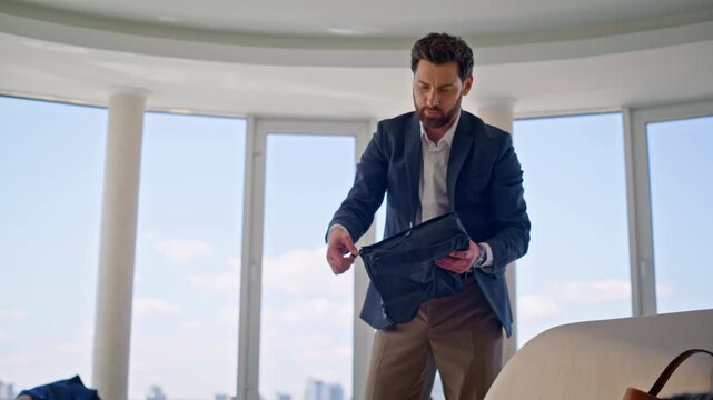 Elegant man packing suitcase luxury apartment. Businessman folding travel jacket