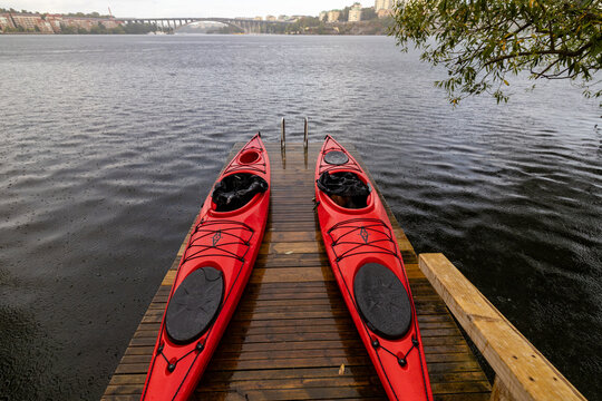 Stockholm, Sweden Two red kayaks sit on a pier in the rain on the Stora Essingen island.