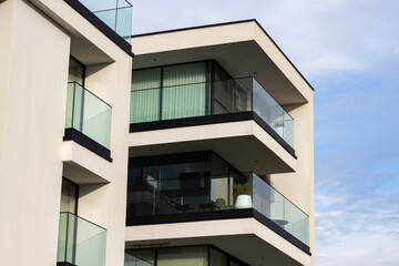 Modern residential building with multiple balconies featuring glass railings and large windows...
