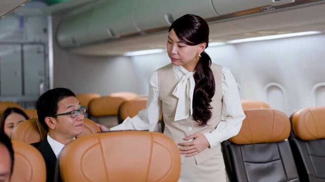 Flight attendant walking through the airplane cabin checking on passengers and ensuring everything is in order during an in-flight service.